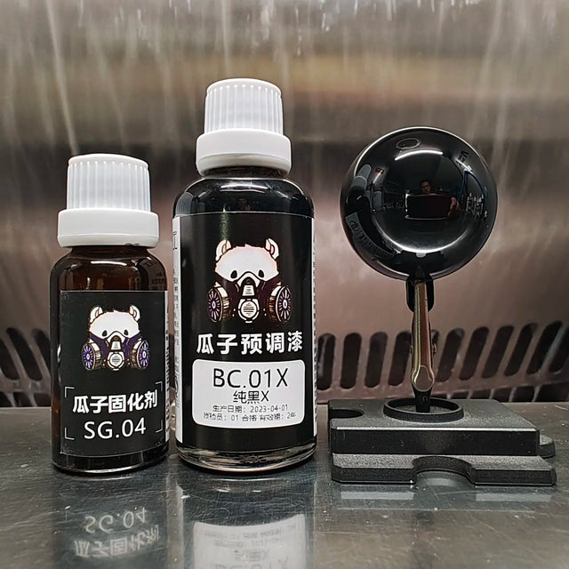 Guazi BC.01X gloss black paint bottle and hardener bottle beside a mirror-black painted sphere