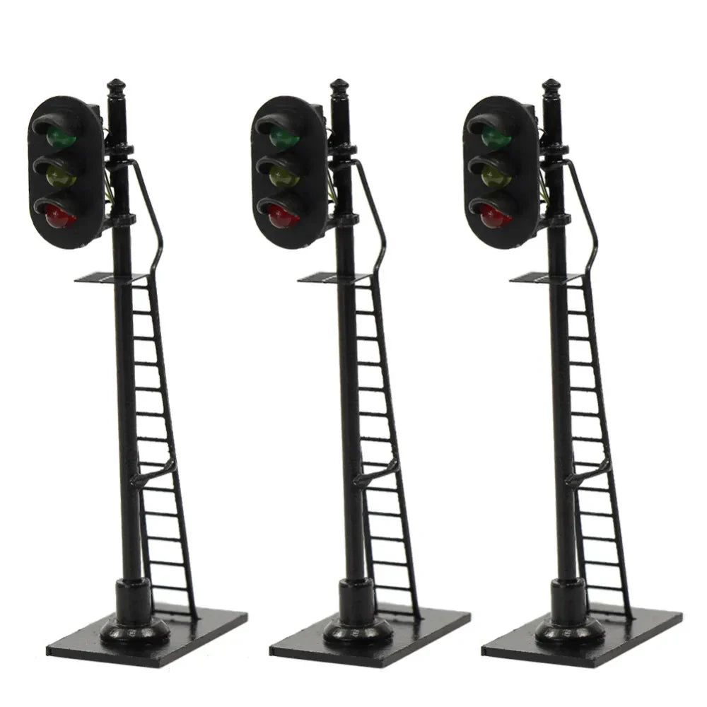 Three black ho scale railway block signals with red and green lights on poles with attached ladders