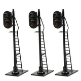 Three black ho scale railway block signals with red and green lights on poles with attached ladders