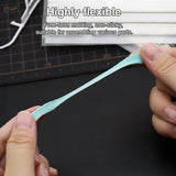 Light blue reusable tack stretched between fingers for scale modeling