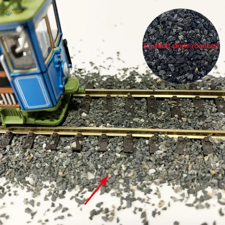 Blue green model train engine on 50g ballast gravel bag track