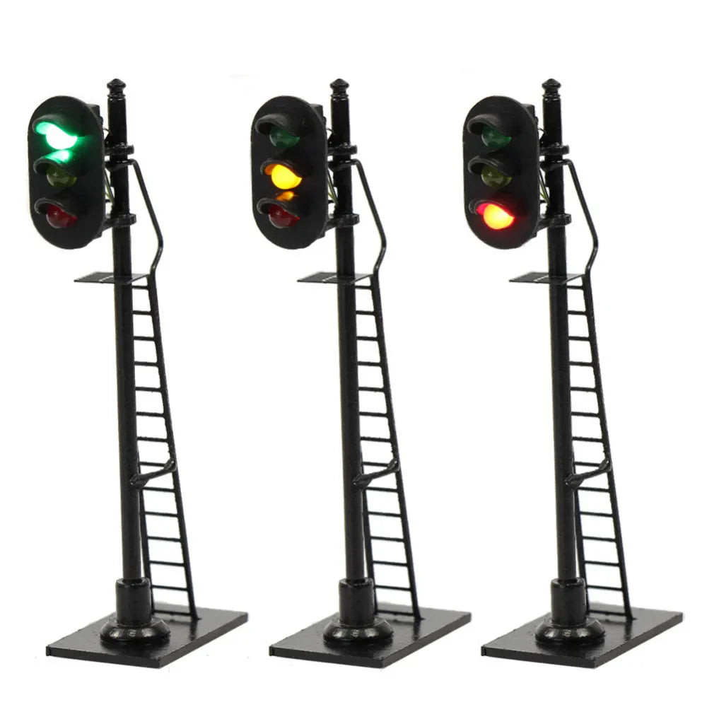 Three black ho scale railway block signals with green yellow red lights mounted on ladders for model trains