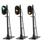 Three black ho scale railway block signals with green yellow red lights mounted on ladders for model trains