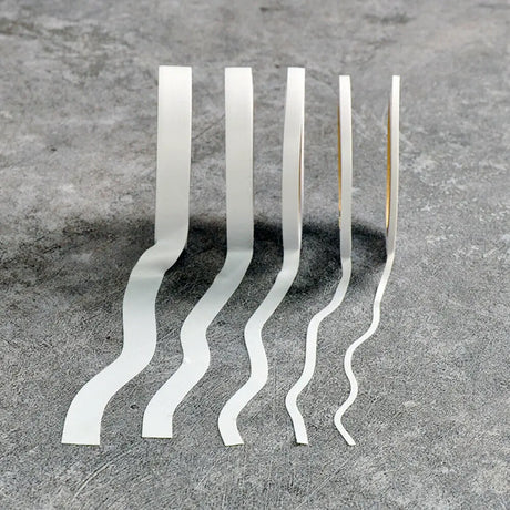 Five white wavy flexible masking tape strips in a row on gray surface