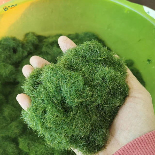 Hand holding 8mm green static grass with vibrant fuzzy moss fibers