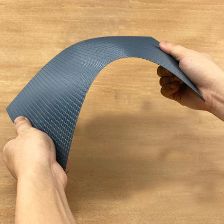 Hands bending flexible dark gray roof simulating PVC panel woven texture