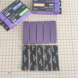 Purple sponge sanding strips and black #600-800 strips arranged in rows beside the four grit boxes