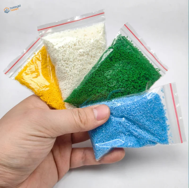 Four clear plastic bags with colored granular crushed coal in a nine-piece scenery starter pack for diorama scenery