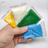 Four clear plastic bags with colored granular crushed coal in a nine-piece scenery starter pack for diorama scenery