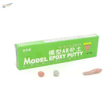 Green rectangular box of ab epoxy putty with pink gray and flesh-toned samples for scale modeling tools and epoxy putty use