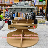 Gray plastic model tank mounted on adjustable wooden painting stand with black clamps and wires for scale modeling tools