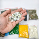 A hand holds smooth light green and white pebbles from a 9pcs diorama scenery material set for scenery starter pack