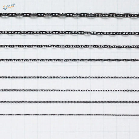 Black metal anchor chains with varying link styles arranged in parallel rows for model ships use