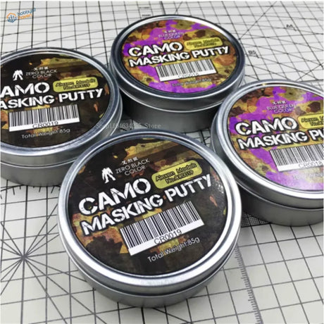 Silver tin containers of soft-edge camouflage masking putty in black and blue-green for effective camouflage masking