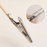 Silver alligator clip with serrated jaws gripping wooden stick, model building tool