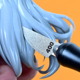 A silver 400-grit curved emery file blade with a black handle refining light blue plastic hair details