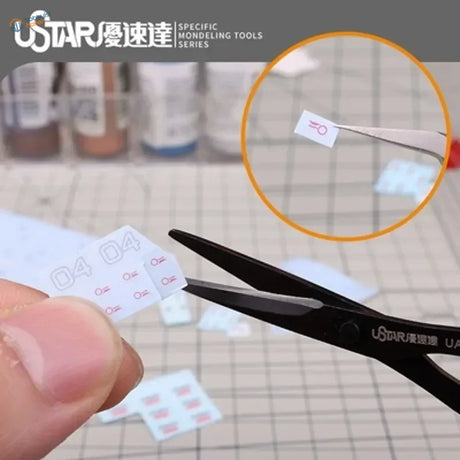 Fine scissors cutting white masking tape sticker with red markings