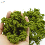 Hand holding vibrant green HO scale tree powder moss for railroad scenery