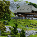 HO scale tree powder with detailed miniature wooden house, gray shingled roof, stone foundation, balconies, windows for railroad scenery