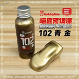 A bottle of hobby mio 50ml oil-based metallic gold paint with a silver cap beside a painted golden object for model building tools