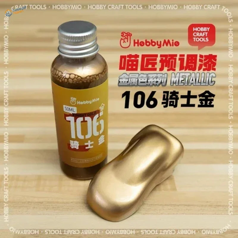A bottle of hobby mio 50ml oil-based metallic gold paint with silver cap and golden applicator for precision hobby tools