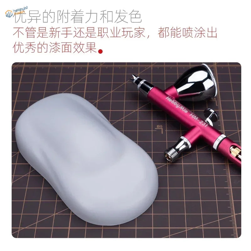 A sleek matte gray hobby mio 50ml primer surfacer pad beside a red chrome airbrush for precision hobby tools and scale modeling tools
