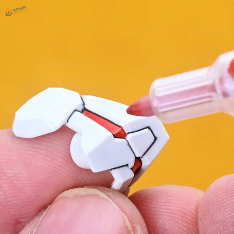 White plastic gundam model part detailed with red accents using lazy master metallic paint markers for precision coloring
