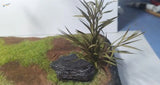 Miniature long leaf shrubs with pointed leaves on textured rock base