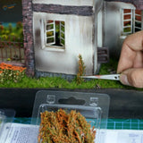 Miniature silver scissors trimming long shrubs foliage for scale modeling dioramas