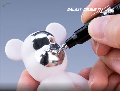 Painting reflective silver face on white glossy plastic bear with metallic color marker pen