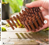A compact brown miniature wooden picket fence made of interlocking wooden pickets for garden and diorama decoration