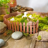 Miniature wooden picket fence with reddish-brown finish featuring thin vertical slats and wire fencing for garden decor