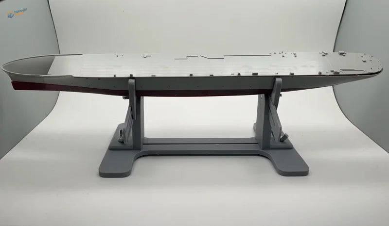 Gray metallic aircraft carrier model on model ship holder stand