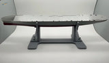 Gray metallic aircraft carrier model on model ship holder stand