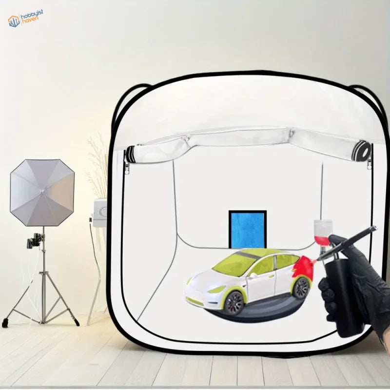 White and lime green tesla model y being painted inside a 30x30in portable spray booth with storage bag for scale modeling