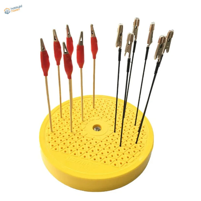 Yellow circular stand with red black alligator clips on rotary painting turntable