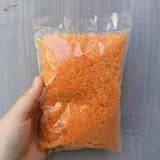 Hand holding bag of orange granules for scale model trees leaves