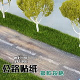 Miniature white-trunked mossy trees lining simulated asphalt stickers road