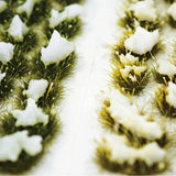 Snowy grass patches with green fuzzy tufts and white snow topping