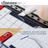 T Shaped Ruler Pro with silver textured blade utility knife on grid mat