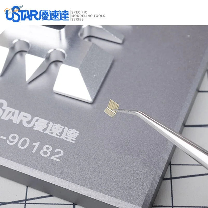 Gold grid-patterned microchip held by tweezers in UStar photoetch bending tool