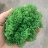 Hand holding 22g Green Tree Powder, vibrant green fluffy moss for scale modeling tools
